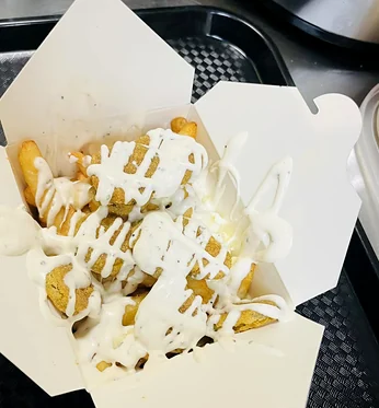 Dill Pickle Poutine: fries topped with crispy fried pickle chips and a ranch drizzle in an open takeout box